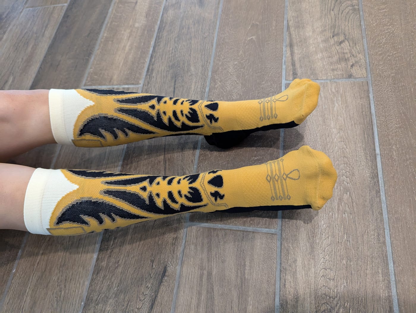 Someone wearing the mustard cowboy boot socks, seen from above on a tiled floor.