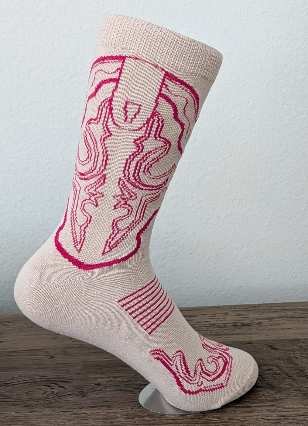A cream cowboy boot sock with hot pink line-drawn western stitching, seen at a three-quarter angle.